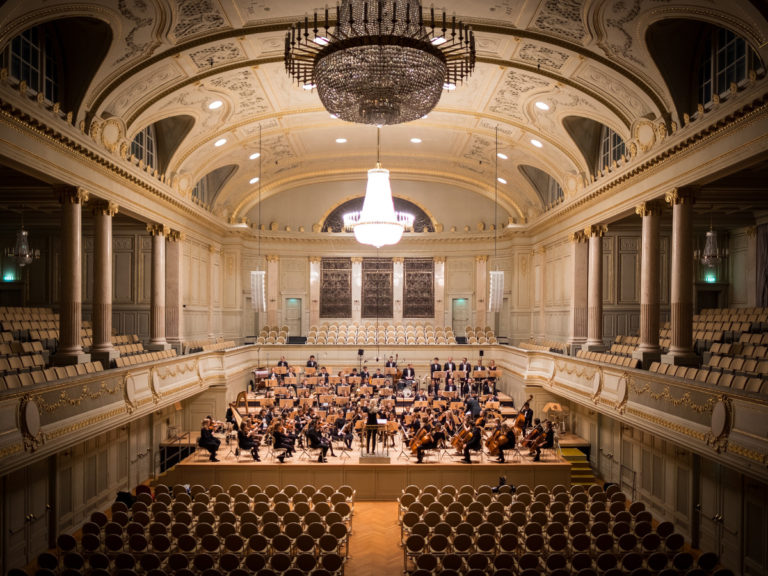Orchestra playing in big hall with empty seats